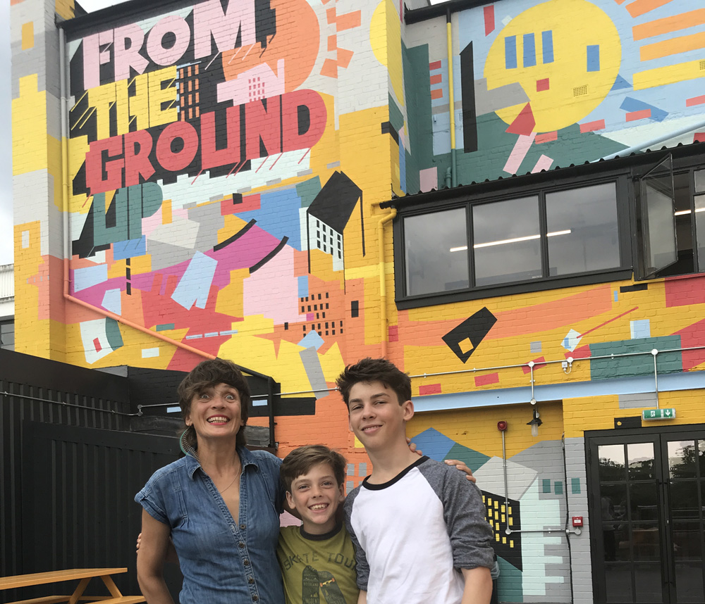 Abi and sons pictured. colourful mural art on background