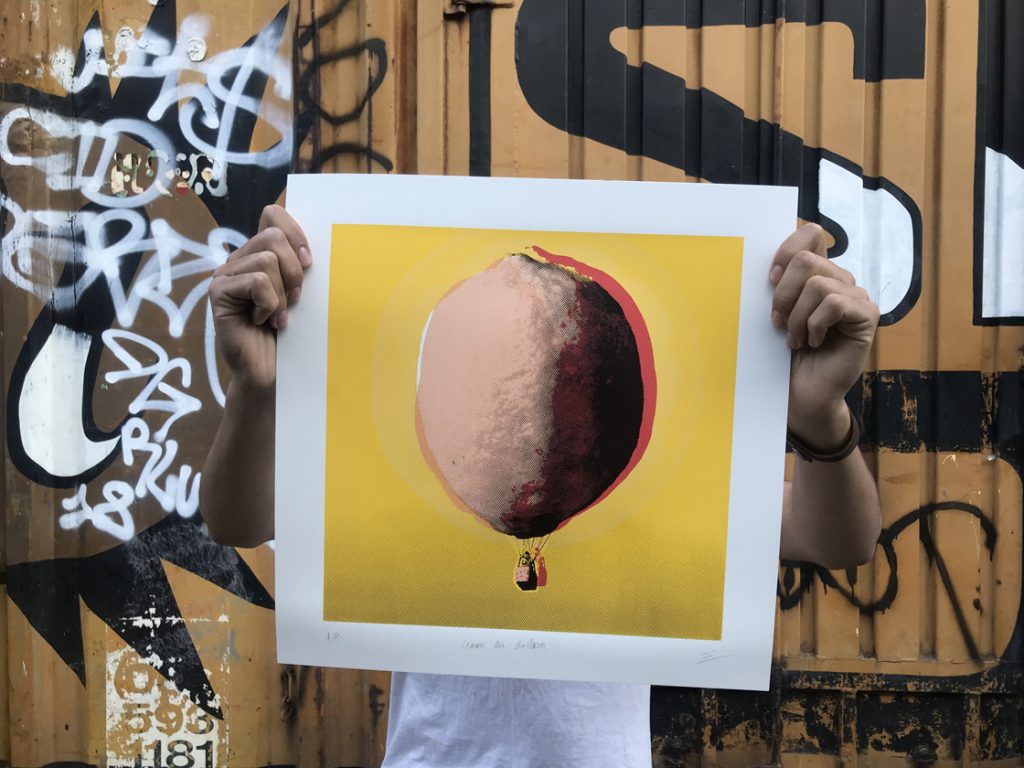 ze monteiro holding a print of air balloon shaped in a lemon, in CHIMPAN zine